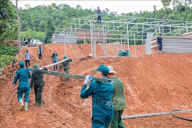 Lực lượng dân quân tự vệ hỗ trợ chuyển vật liệu thi công xây lắp nhà tạm khu tái định cư mới cho người dân thôn Làng Nủ (xã Phúc Khánh, huyện Bảo Yên, tỉnh Lào Cai). Ảnh: Hoàng Hiếu - TTXVN