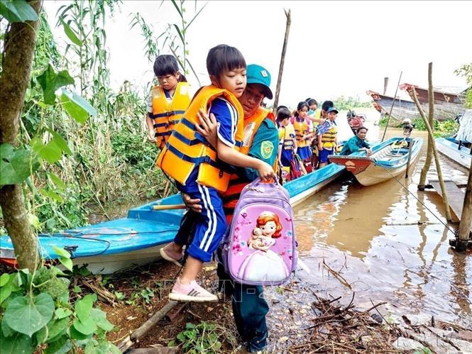 Lực lượng dân quân tự vệ xã Vĩnh Hội Đông (An Giang) chịu trách nhiệm đưa đón các học sinh Trường tiểu học B Vĩnh Hội Đông ở 2 ấp Vĩnh Hòa và Vĩnh An về nhà an toàn trong mùa mưa lũ (10/2022). Ảnh: Công Mạo-TTXVN