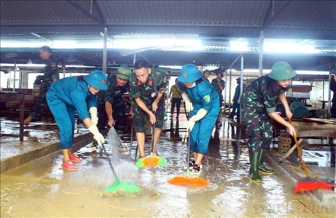 Lực lượng quân đội, dân quân tự vệ dọn vệ sinh, khắc phục hậu quả do mưa lũ gây ra tại chợ xã Thanh Mỹ (huyện Thanh Chương, Nghệ An) (10/2022). Ảnh: Tá Chuyên – TTXVN