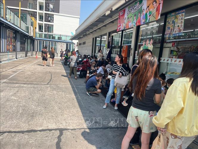 Người dân trú tạm dưới bóng râm của cửa hàng tiện lợi chờ đến khi được phép trở lại nhà. Ảnh: Huy Tiến - PV TTXVN tại Thái Lan