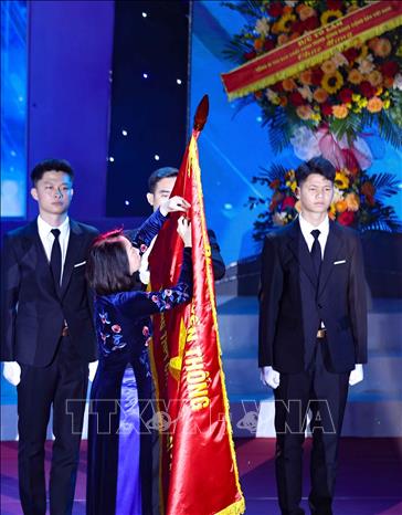 Thừa ủy quyền của Chủ tịch nước, Phó Chủ tịch UBND thành phố Hà Nội Vũ Thu Hà gắn Huân chương Lao động hạng Nhất lên cờ truyền thống của trường THPT Chuyên Hà Nội - Amsterdam. Ảnh: Thanh Tùng - TTXVN