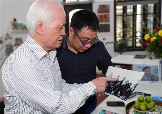 Đại tá phi công Hoàng Biểu giới thiệu những hình ảnh Thủ tướng Phạm Văn Đồng về đơn vị thăm, chúc mừng sau những chiến công của các anh. Ảnh: Trọng Đức - TTXVN