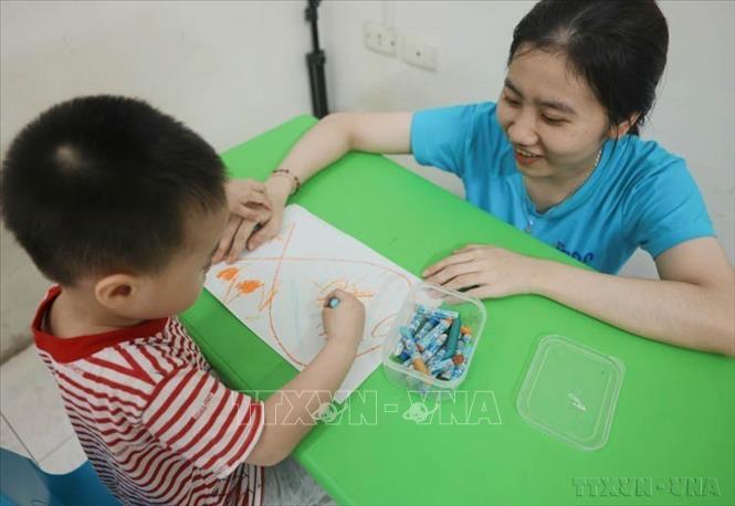 Cô giáo Nguyễn Thị Thúy Hằng (Trung tâm tư vấn và giáo dục hòa nhập Gia An) can thiệp 1 -1 với trẻ 3 tuổi bị rối loạn phổ tự kỷ (ASD). Ảnh: Hoàng Hiếu - TTXVN