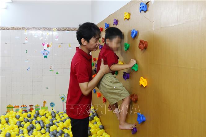 Giáo viên can thiệp về vận động cho trẻ tại Trung tâm Can thiệp và trị liệu tâm lý EMH. Ảnh: Lê Xuân-TTXVN
