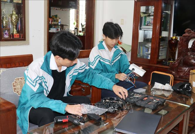 Em Cao Trung Quân và Lê Minh Hiếu lắp ráp chiếc xe lăn tự hành dành cho người bị mắc bệnh xơ cứng teo cơ. Ảnh: Thanh Thuỷ-TTXVN