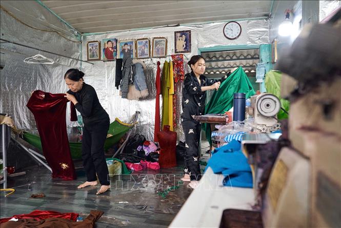 Các thế hệ làng nghề Trạch Xá vẫn miệt mài gìn giữ lối cắt may truyền thống.. Ảnh: Lê Đông - TTXVN 