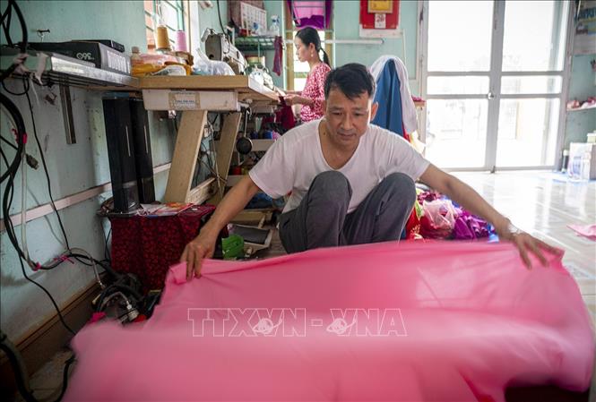 Một trong những đặc trưng khác làm nên thương hiệu của làng Trạch Xá đó chính là việc không dùng chỉ công nghiệp mà dùng chính những sợi tơ gỡ ra từ tấm vải may áo dài. Với cách làm này, chiếc áo sẽ đồng nhất về chất liệu, không bị cứng hay co giãn khi giặt, tà áo luôn giữ được sự thướt tha, mềm mại. Ảnh: Khánh Hoà - TTXVN 