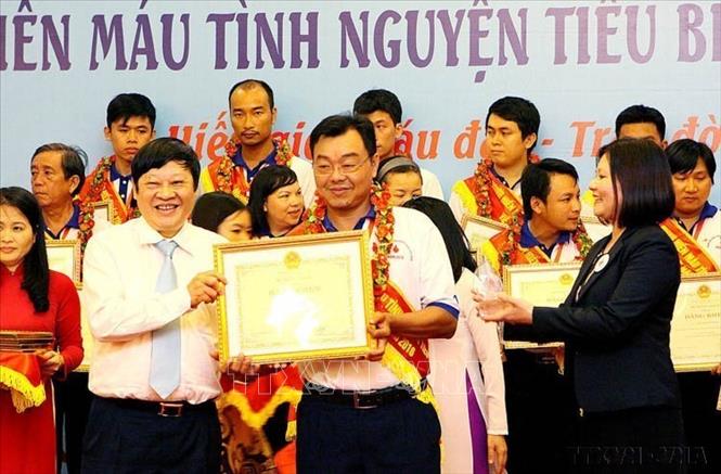 Thứ trưởng Bộ Y tế Nguyễn Viết Tiến tôn vinh anh Nguyễn Hữu Thuận (TP. Hồ Chí Minh) 85 lần hiến máu tình nguyện tại Lễ tôn vinh người hiến máu tình nguyện tiêu biểu năm 2016. Ảnh: Dương Ngọc - TTXVN