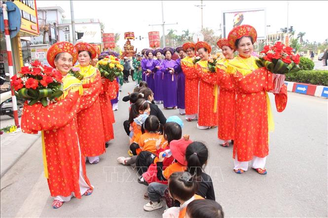 Người dân ngồi xếp hàng chờ chui kiệu để cầu mong may mắn, sức khỏe. Ảnh: Ngọc Thanh/TTXVN phát