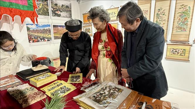 Artisan Nguyen Dang Tam introduces the art of making Dong Ho folk paintings to visitors in Paris. VNA Photo: Nguyễn Thu Hà