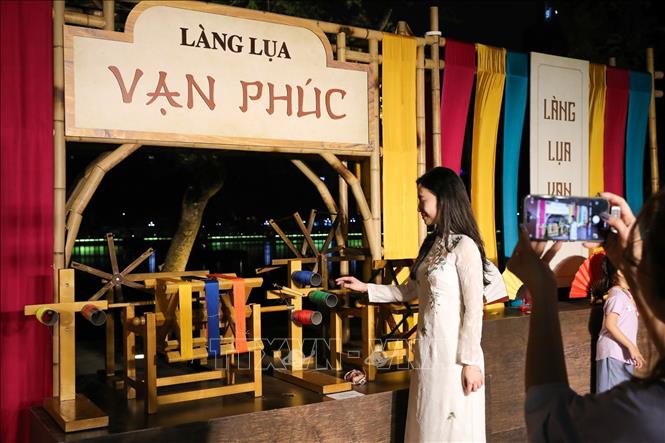 Người dân chụp ảnh lưu lại khoảnh khắc tại gian trưng bày của làng lụa Vạn Phúc. Ảnh: Khánh Hoà - TTXVN
