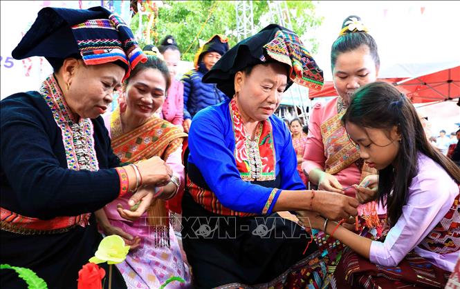 A ritual of tying thread on wrists to pray for good luck at the festival. VNA Photo: Trung Kiên