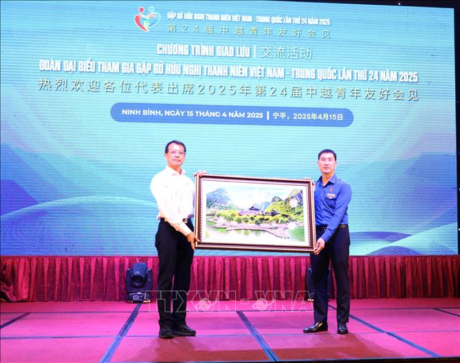 Ông Trịnh Như Lâm, Bí thư Tỉnh đoàn Ninh Bình (áo xanh) tặng bức tranh phong cảnh Tràng An cho đại diện đoàn đại biểu thanh niên Trung Quốc. Ảnh: Thùy Dung - TTXVN
