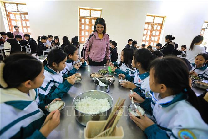 Cô giáo Hiệu phó Trường PTDTBT TH & THCS Vầy Nưa Hà Thị Dự cùng các học sinh trong bữa ăn bán trú tại trường. Ảnh: Trọng Đạt-TTXVN