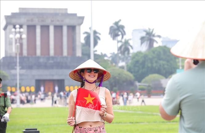 Khách nước ngoài thích thú chụp ảnh cùng lá cờ Việt Nam. Ảnh: Khánh Hoà - TTXVN