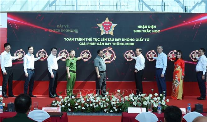 Thủ tướng Phạm Minh Chính và các đại biểu thực hiện nghi thức triển khai thí điểm giải pháp ứng dụng định danh, xác thực điện tử và nhận diện sinh trắc học phục vụ thủ tục lên tàu bay. Ảnh: Dương Giang-TTXVN