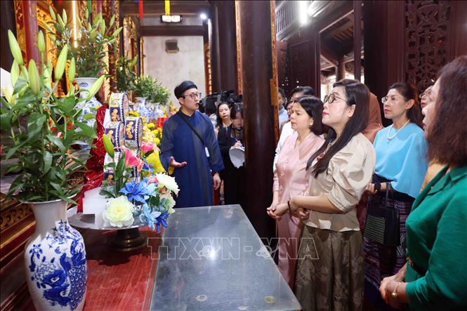 Bà Lê Thị Bích Trân, Phu nhân Thủ tướng Chính phủ Phạm Minh Chính và Nhóm Phụ nữ cộng đồng ASEAN tại Hà Nội nghe giới thiệu về lịch sử Đền Đô. Ảnh: Phạm Kiên - TTXVN
