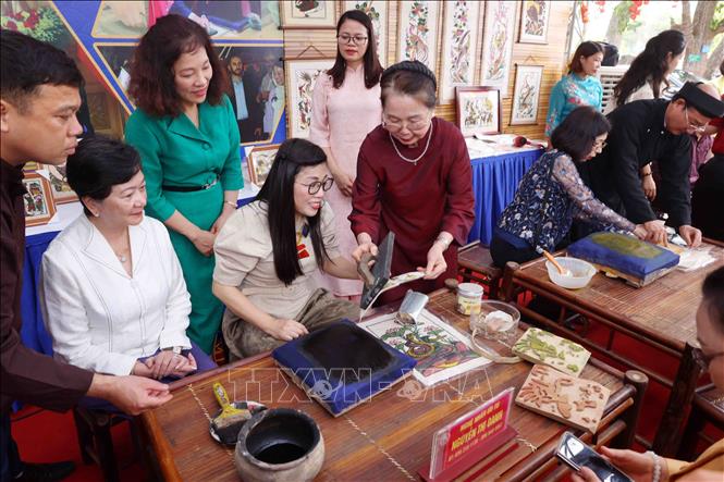Bà Lê Thị Bích Trân, Phu nhân Thủ tướng Chính phủ Phạm Minh Chính và nhóm Phụ nữ cộng đồng ASEAN tại Hà Nội trải nghiệm làm tranh dân gian Đông Hồ. Ảnh: Phạm Kiên - TTXVN