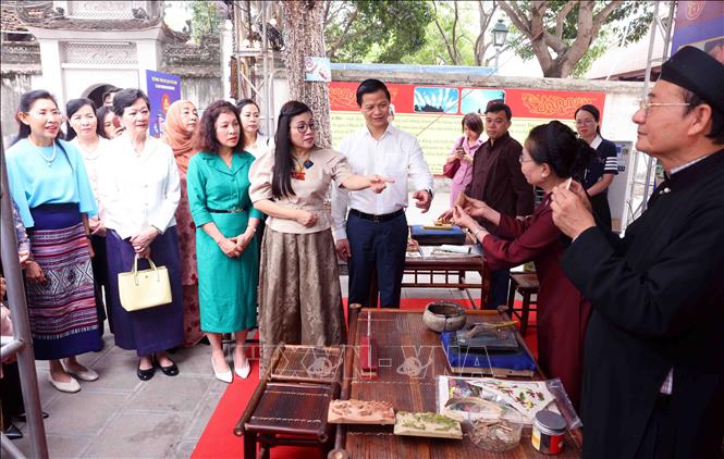 Bà Lê Thị Bích Trân, Phu nhân Thủ tướng Chính phủ Phạm Minh Chính và nhóm Phụ nữ cộng đồng ASEAN tại Hà Nội nghe các nghệ nhân giới thiệu về làm tranh dân gian Đông Hồ. Ảnh: Phạm Kiên - TTXVN