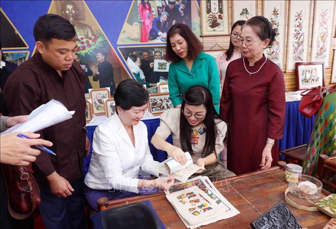 Bà Lê Thị Bích Trân, Phu nhân Thủ tướng Chính phủ Phạm Minh Chính và nhóm Phụ nữ cộng đồng ASEAN tại Hà Nội trải nghiệm làm tranh dân gian Đông Hồ. Ảnh: Phạm Kiên - TTXVN