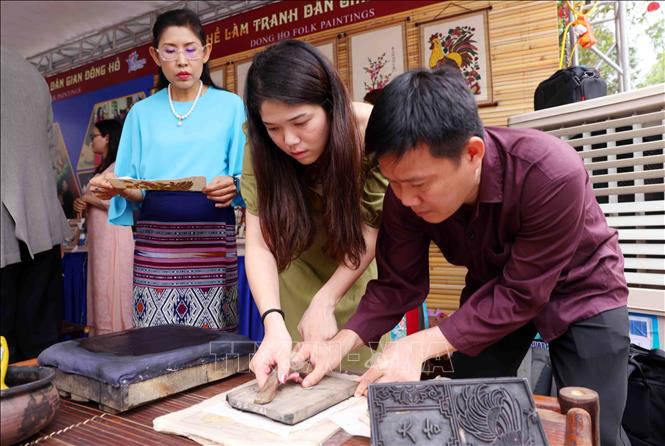Các đại biểu thuộc nhóm Phụ nữ cộng đồng ASEAN tại Hà Nội trải nghiệm làm tranh dân gian Đông Hồ. Ảnh: Phạm Kiên - TTXVN