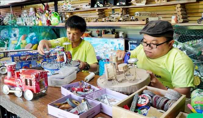 Các thành viên “Vườn tái chế - NNC” tạo ra các sản phẩm có ích, đa năng, hữu dụng từ rác thải (vỏ lon nhôm, chai nhựa, bì carton, vải vụn...). Ảnh: Lê Phước Ngọc - TTXVN
