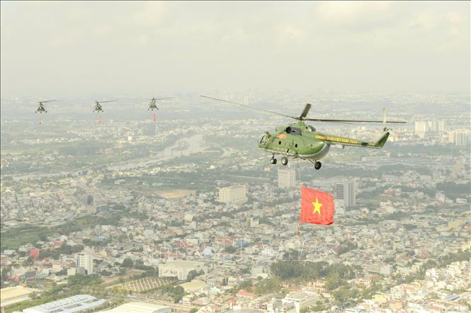  Biên đội máy bay trực thăng mang theo cờ Tổ quốc, cờ Đảng bay trên bầu trời TP Hồ Chí Minh. Ảnh: Mạnh Linh-TTXVN

