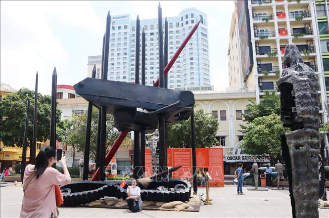 Người dân chụp hình kỷ niệm bên mô hình xe tăng treo ngược. Ảnh: Thu Hương - TTXVN