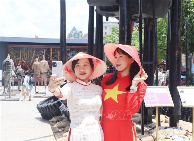 Người dân diện áo dài truyền thống, cờ đỏ sao vàng ghi lại những khoảnh khắc đẹp trong dịp lễ kỷ niệm. Ảnh: Thu Hương - TTXVN