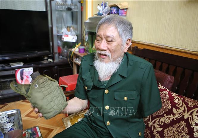Ông Nguyễn Thế Tám nâng niu chiến tích tịch thu được của quân địch trong thời gian tham gia giải phóng Sài Gòn. Ảnh: Công Luật - TTXVN