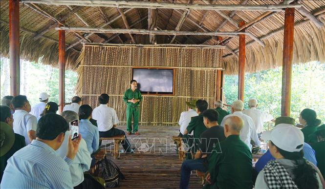 Du khách chăm chú nghe thuyết minh viên giới thiệu về những trận đánh vang dội khiến kẻ thù khiếp sợ của các chiến sĩ Đặc công Rừng Sác. Ảnh: Hữu Duyên - TTXVN