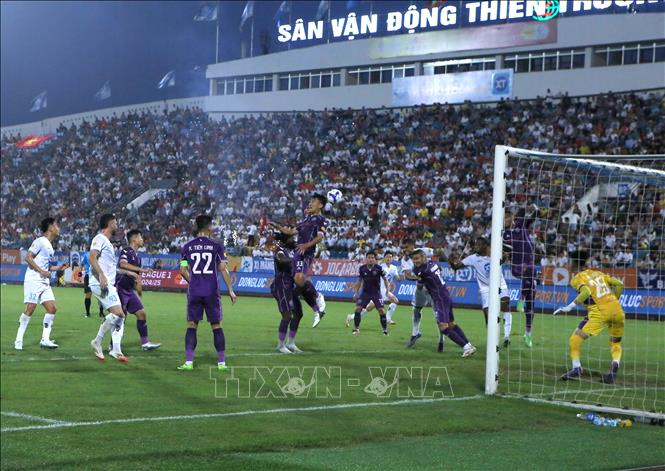 Tình huống tranh chấp bóng giữa các cầu thủ Thép Xanh Nam Định (áo trắng) và các cầu thủ Bình Dương. Ảnh: Công Luật - TTXVN