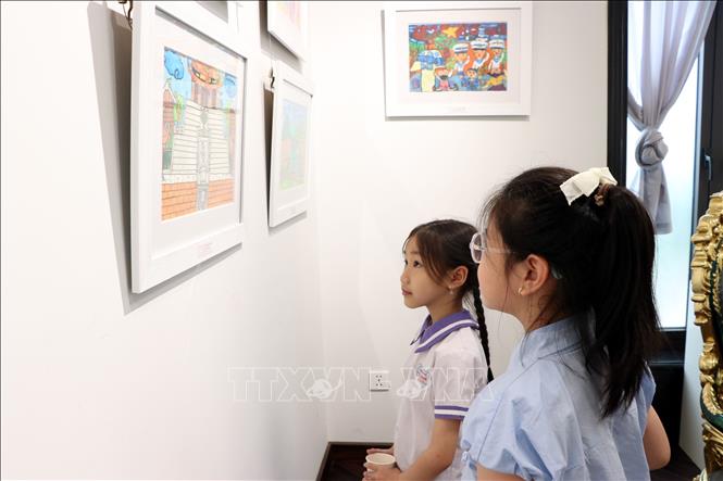 Học sinh xem các bức vẽ trưng bày tại triển lãm. Ảnh: Mạnh Tú - TTXVN