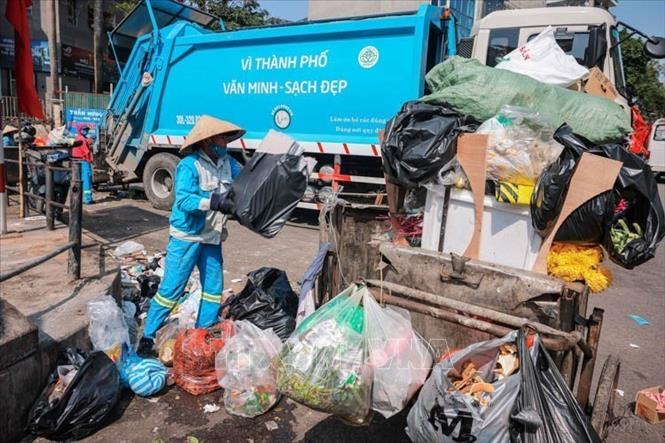 Những công nhân thầm lặng, miệt mài quét dọn, thu gom rác, đảm bảo không gian sạch đẹp cho Thủ đô trong những ngày Tết Ất Tỵ. Ảnh: Hoàng Hiếu - TTXVN