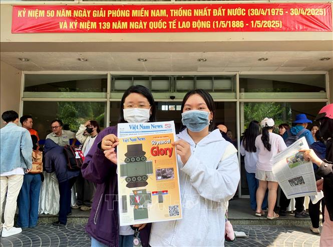 Hoàng Hà và Bảo Ngọc, sinh viên năm 2 trường Đại học Kinh tế - Luật (Đại học Quốc gia Thành phố Hồ Chí Minh) mua chung nhau ấn phẩm Mô hình cắt dán xe tăng 390. Ảnh: Hồng Đạt - TTXVN
