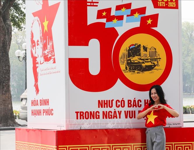 Người dân check-in với áp phích cổ động trên đường Đinh Tiên Hoàng, quận Hoàn Kiếm. Ảnh: Khánh Hoà - TTXVN