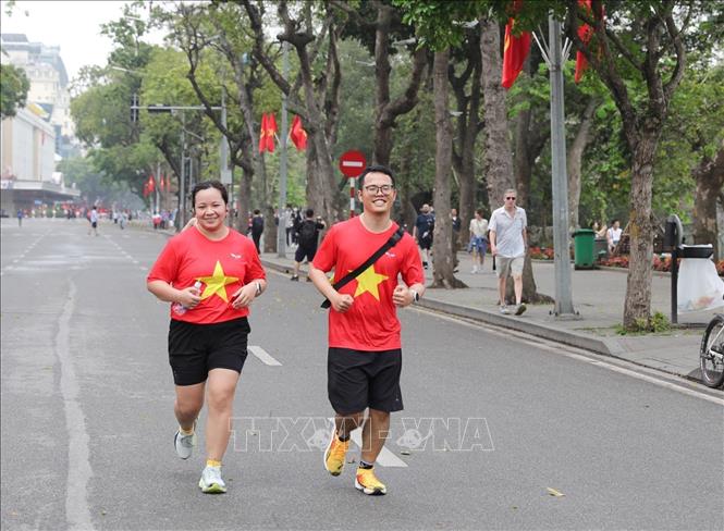 Nhiều người dân chọn cho mình trang phục có hình cờ đỏ sao vàng trong ngày này thể hiện sự tự hào kỷ niệm 50 năm thống nhất đất nước. Ảnh: Khánh Hoà - TTXVN