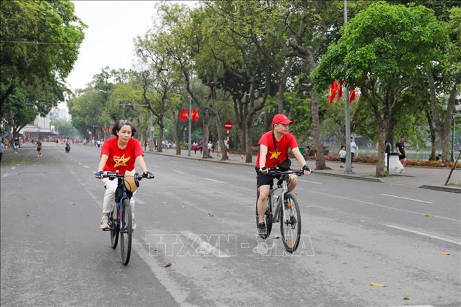 Nhiều người dân chọn cho mình trang phục có hình cờ đỏ sao vàng trong ngày này thể hiện sự tự hào kỷ niệm 50 năm thống nhất đất nước. Ảnh: Khánh Hoà - TTXVN