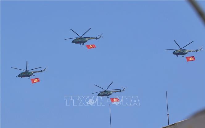 Biên đội trực thăng mang theo cờ Đảng, cờ Tổ quốc bay trên bầu trời trung tâm Thành phố Hồ chí Minh. Ảnh: Hồng Giang - TTXVN
