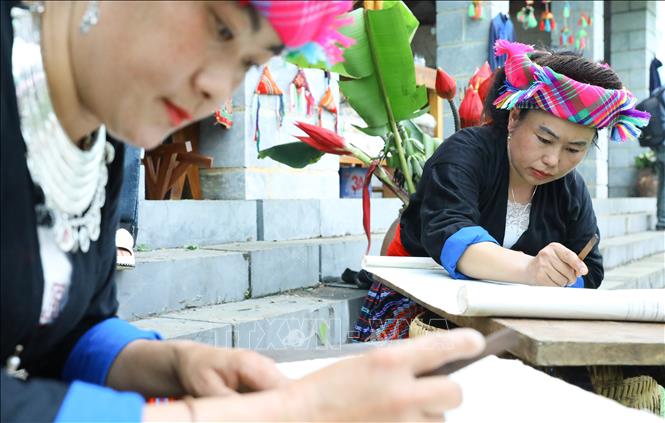 Đồng bào dân tộc Mông trong trang phục truyền thống trình diễn in sáp ong tại sự kiện. Ảnh: Lê Đông – TTXVN
