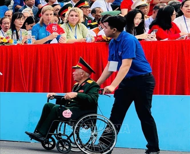  Thanh niên hỗ trợ đại biểu di chuyển trong khu vực Lễ diễu binh, diễu hành kỷ niệm 50 năm Ngày Giải phóng miền Nam, thống nhất đất nước. Ảnh: Tấn Đạt - TTXVN