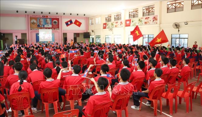 Học sinh Trưởng song ngữ Lào-Việt Nam Nguyễn Du hào hứng vẫy cờ khi được xem truyền hình trực tiếp Lễ kỷ niệm 50 năm Giải phóng miền Nam, thống nhất đất nước tại trường. Ảnh: Xuân Tú - PV TTXVN tại Lào
