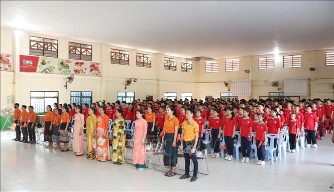 Thầy trò Trường song ngữ Lào-Việt Nam Nguyễn Du thực hiện nghi thức Chào cờ trước giờ xem truyền hình trực tiếp Lễ kỷ niệm 50 năm Giải phóng miền Nam, thống nhất đất nước. Ảnh: Xuân Tú - PV TTXVN tại Lào