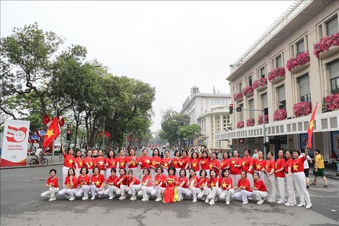  Nhiều người dân Thủ đô chọn cho mình trang phục có hình cờ đỏ sao vàng trong ngày này thể hiện sự tự hào kỷ niệm 50 năm thống nhất đất nước. Ảnh: Khánh Hoà - TTXVN