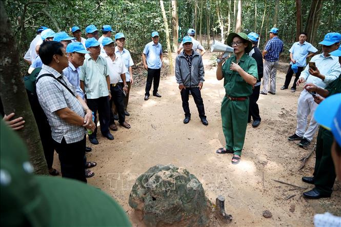 Khách tham quan tìm hiểu lỗ thông hơi địa đạo Củ Chi. Ảnh: Hồng Đạt - TTXVN

