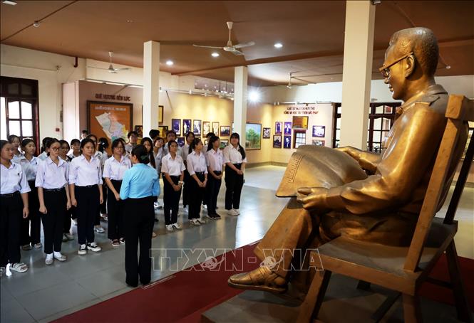 Học sinh tỉnh Long An nghe giới thiệu bên bức tượng Luật sư Nguyễn Hữu Thọ đọc báo ở chiến khu. Ảnh: Hồng Đạt - TTXVN