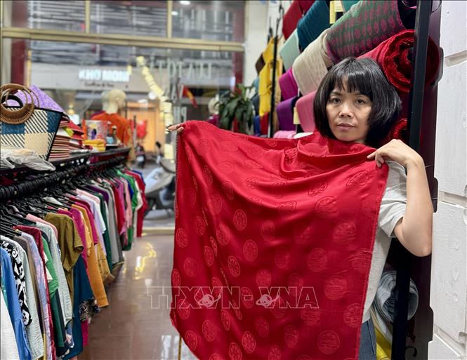 Chị Hoàng Thị Tươi giới thiệu mẫu vải lụa in biểu tượng thành phố Hải Phòng. Ảnh: Minh Huệ-TTXVN