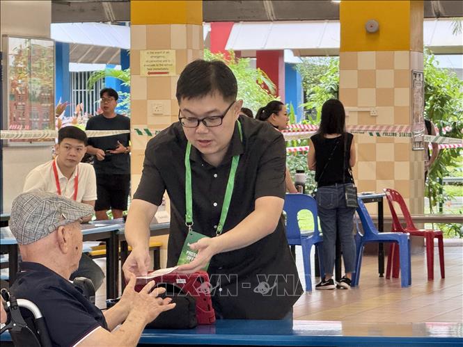 Cử tri ngồi xe lăn được các nhân viên bầu cử hỗ trợ nhiệt tình. Ảnh: Đỗ Vân - PV TTXVN tại Singapore
