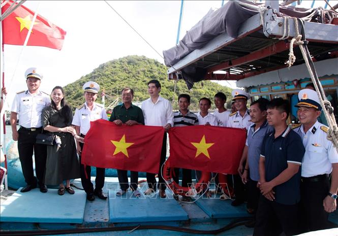 Lực lượng Hải quân Vùng 4 và các nhà hảo tâm trao tặng cờ Tổ quốc cho ngư dân. Ảnh: TTXVN phát