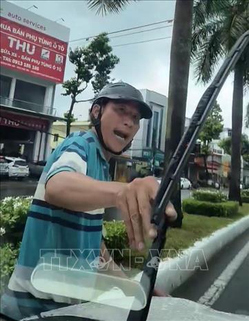Người đàn ông dùng tay bẻ cần gạt nước của ô tô được người trên xe ô tô quay video lại. Ảnh: TTXVN phát